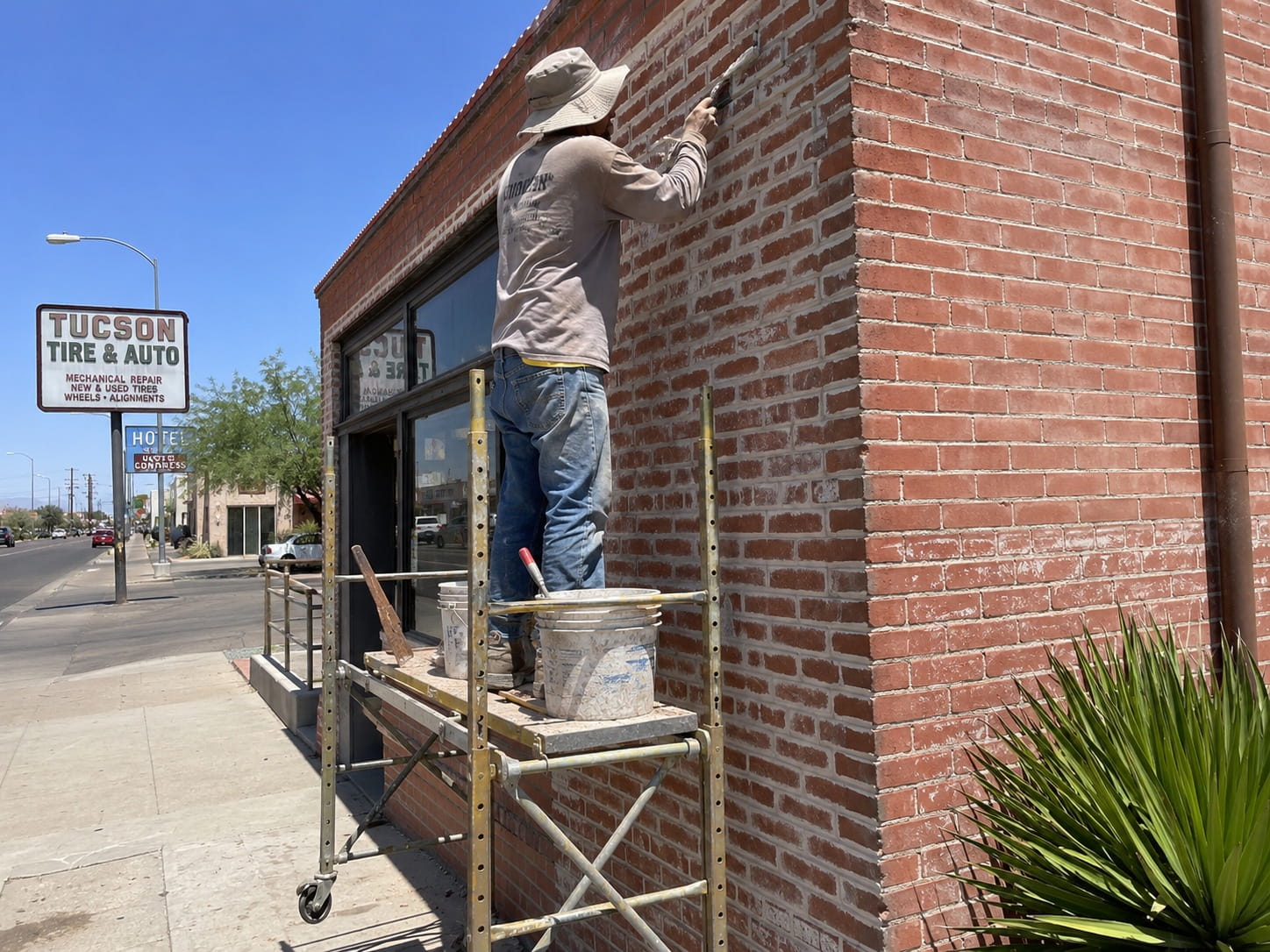 Masonry contractor working on a commercial brick building corner in Tucson